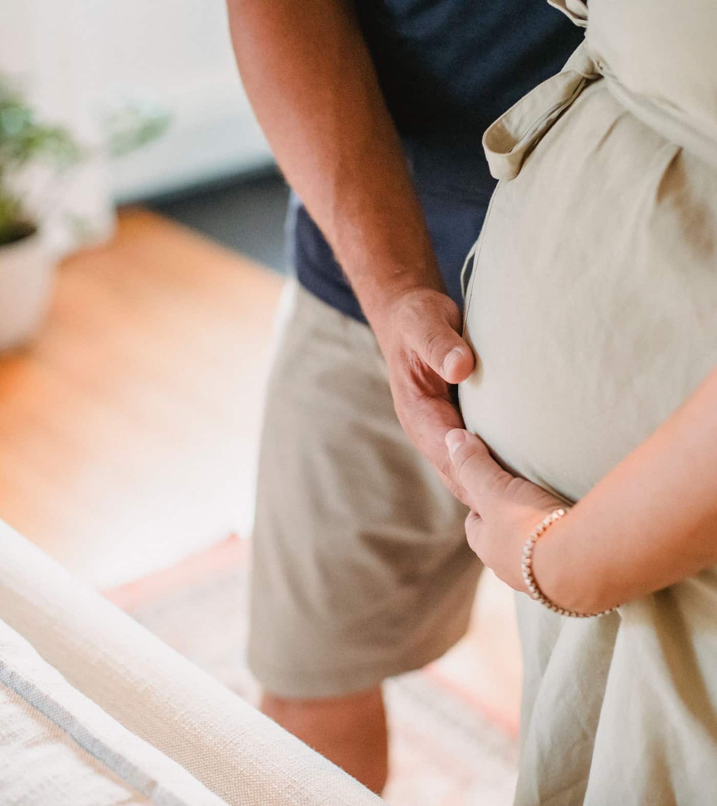 Casal acariciando com carinho a barriga da gestante, em casa
